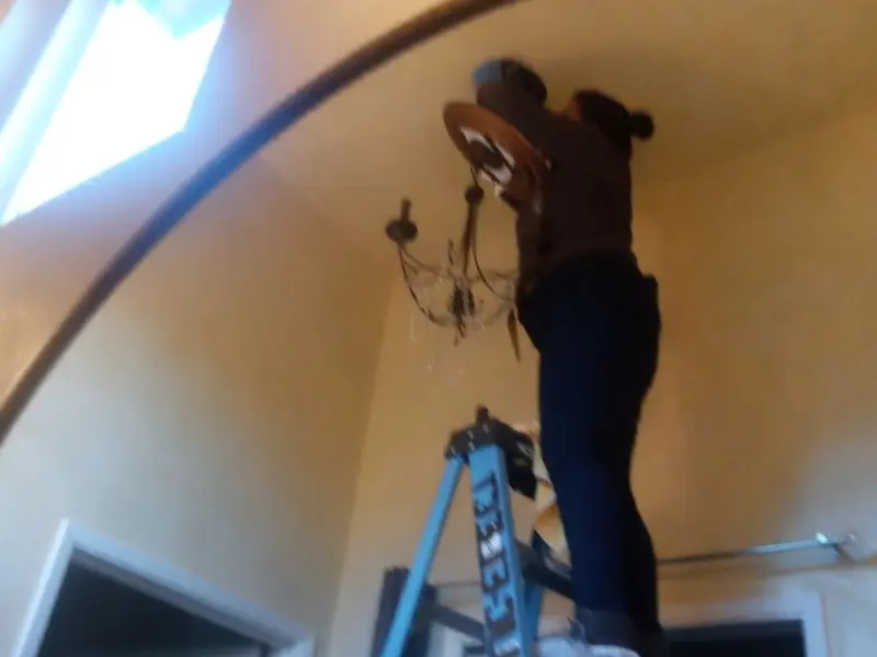 Electrician installing a chandelier in a Dwight residence
